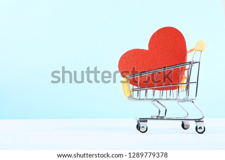 Shopping cart with red heart on wooden table