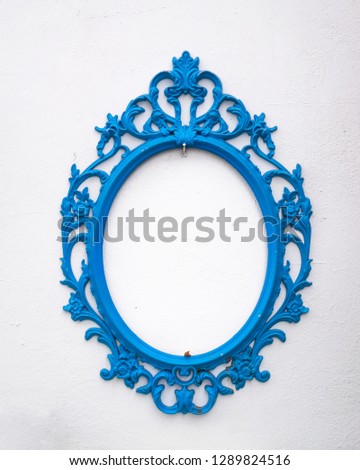 White wall and empty oval blue mirror. Decorative retro frame.