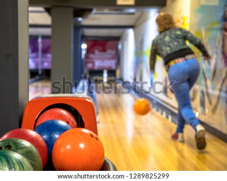 Female bowler throwing bowling ball on indoor bowling alley