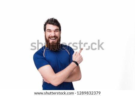 Handsome bearded man pointing away to copy space and looking at the camera