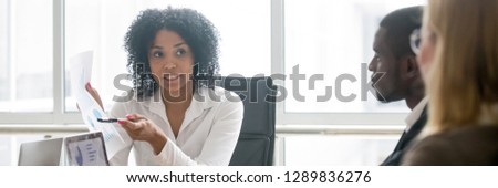 Horizontal photo multiracial people led by african businesswoman, leader showing paper financial report to clients partners negotiating at meeting sitting a boardroom, banner for website header design Royalty-Free Stock Photo #1289836276