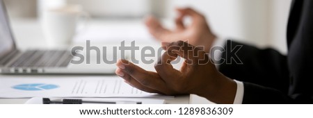 Close up african businessman sitting at desk near laptop stress relief at workplace, mental health internal balance concept, horizontal photo banner for website header design with copy space for text