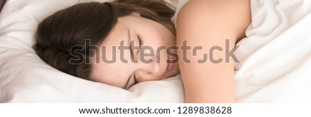 Close up young attractive woman lying in bed sleeping resting at home or hotel enjoy comfortable soft cotton linen fresh bedding dreaming feels good. Horizontal photo banner for website header design