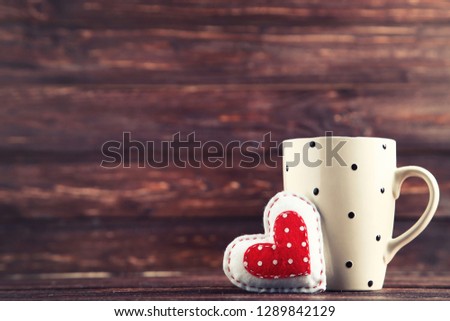 Fabric heart with cup on brown wooden table