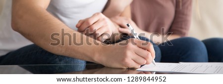 Horizontal photo couple close up man hand holds pen put signature signing rental agreement, real estate purchase, buy first time new home prenuptial agreement concept, banner for website header design