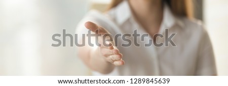 Businesswoman holds out her hand to camera for handshake, arm close up. Greeting negotiations first acquaintance hr concept. Horizontal photo banner for website header design with copy space for text