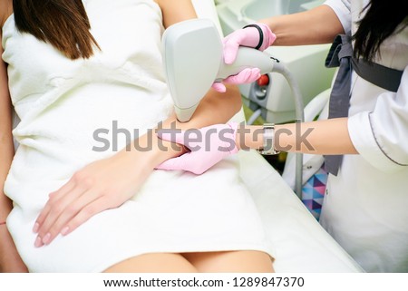 A cosmetologist carries out a procedure for laser hair removal from the body of a girl. Laser hair removal. Cosmology. Hand hair removal Royalty-Free Stock Photo #1289847370