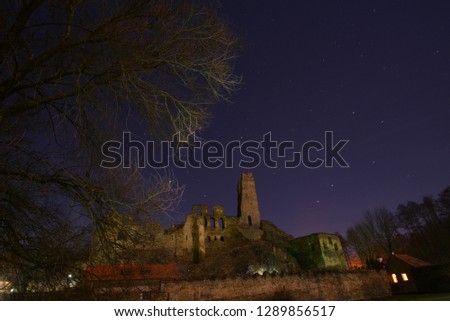Old castle ruin under sky with stars at night.