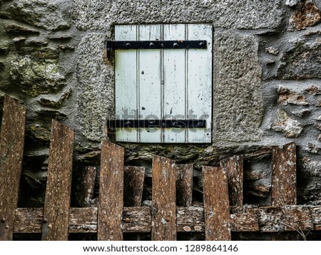 The window of an old European country house with walls of stones and a wooden fence. Retro style.