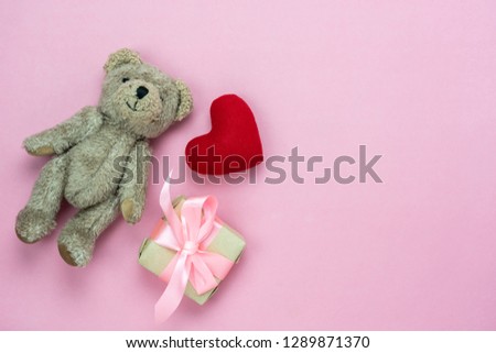 Table top view aerial image of decoration valentine's day background concept.Flat lay essential items love red heart & gift box with bear doll toy kid on modern rustic pink paper with copy space.