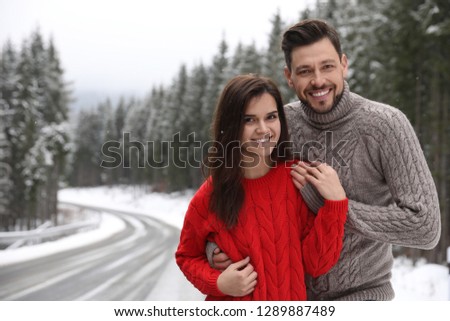 Cute couple outdoors on snowy day, space for text. Winter vacation