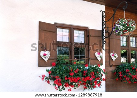 The windows of the wooden house are beautifully decorated with white hearts and flowers.