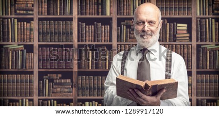 Senior academic professor reading an old book in the library, knowledge, learning and education concept