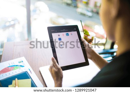 Businesswoman using applications on contemporary touch pad while sitting at desktop in office interior. Female CEO received notifications on digital tablet. Online banking via computer 