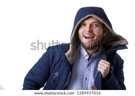 Smiling young guy in winter warm coat. Fashionable man wearing blue winter jacket