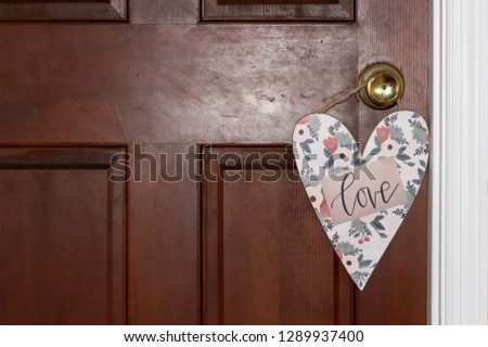 Heart sign hanging on a door knob that reads love