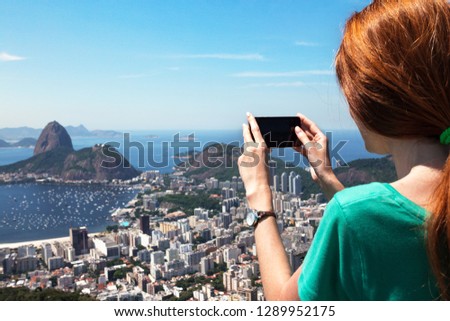 girl tourist  takes a picture of  Rio landscape and Pao de Asucar with smartphone, Brazil
