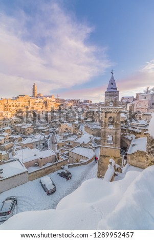 panoramic view of typical stones Sassi di Matera and church of Matera 2019 under blue sky with clouds and snow on the house, travel and christmas holiday on snowflakes,capital of europe culture 2019
