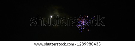 web banner with free space for white text shows lilac fireworks and blurred moon on New Year's Eve with deep dark background