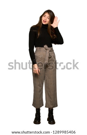 Full-length shot of Pretty girl listening to something by putting hand on the ear on isolated white background
