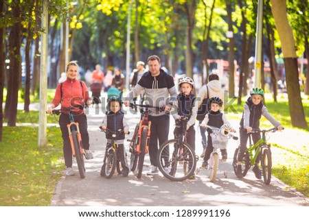 Theme family active sports outdoor recreation. A group of people is a big family of 6 people standing posing on mountain bikes in a city park on a road on a sunny day in autumn.