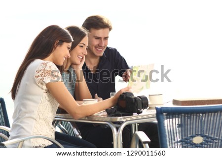 Three happy tourists checking guide sitting in a coffee shop on vacation