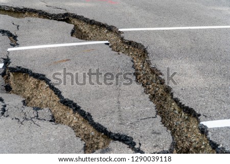 Damaged parking lot collapses with huge cracks by natural disaster. Asphalt parking lot collapse and falling down until found structure from bad construction.
