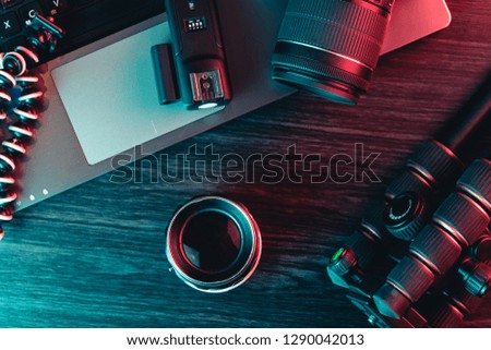 Top view of a desk working with laptop keyboard, modern camera, lens, tripod and a black pen on a wood background. Freelance, creative or online education concept