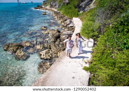 Couple in white clothes or newlyweds run side by side playfully by the seashore. Drone view. Honey moon concept. Romantic concept.  Holidays in a tropical country.  Royalty-Free Stock Photo #1290052402