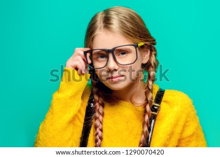 Cute nine year old girl posing in studio in fluffy yellow dress over turquoise background. Children's beauty and fashion.