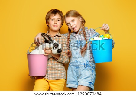 Happy children are posing with Easter attributes on yellow  background. Happy childhood. Easter decorations. 