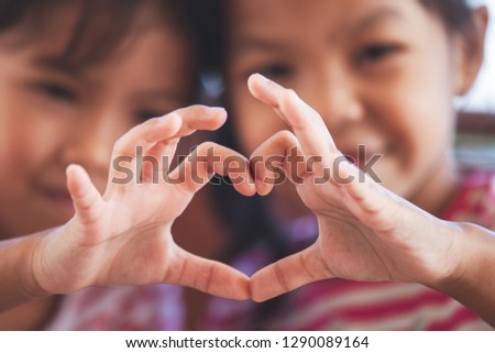 Two cute asian child girls making heart shape with hands together with love Royalty-Free Stock Photo #1290089164