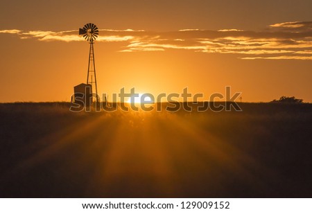 The sun sets near a windmill in the Texas Hill Country Royalty-Free Stock Photo #129009152