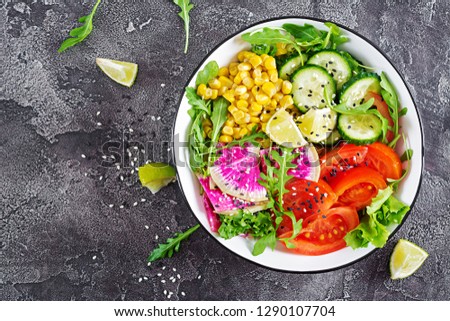 Vegan buddha bowl. Bowl with fresh raw vegetables - cucumber, tomato, watermelon radish, lettuce, arugula and corn. Fresh salad. Vegetarian food. Top view. Flat lay