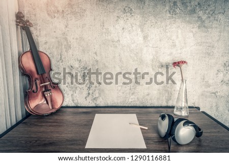 song writing concept. violin, blank paper, headphone on wooden desk. copy space on wall