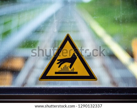 Yellow triangle shape sticker on a window with a hand and heat symbol