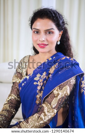 Image of pretty girl wearing blue saree clothes while looking at the camera and sitting at home 
