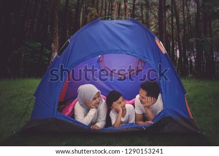 Picture of young parents camping in the forest while lying with their son in the tent