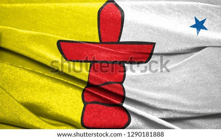 Realistic flag of Nunavut on the wavy surface of fabric. Perfect for background or texture purposes