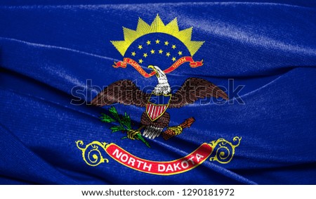 Realistic flag State of North Dakota on the wavy surface of fabric. Perfect for background or texture purposes