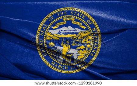 Realistic flag State of Nebraska on the wavy surface of fabric. Perfect for background or texture purposes