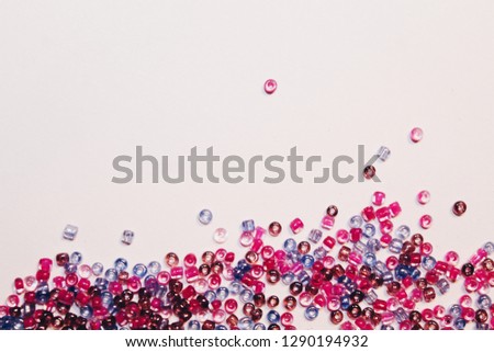 multicolored pink scattered seed beads on white background with space, close up 