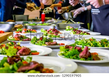 Cooked Roast Beef, Fresh Salad And Tomatoes Served On White Plates. Cooking Master Class, Workshop with People Learning How to Cook Around the Table Royalty-Free Stock Photo #1290197905