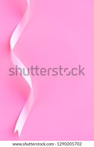 Pink ribbon swirling and free copy space on pink background.