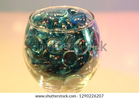 Blue glass circle pieces marbles in wine glass on granite quartz counter top with tile back splash. 