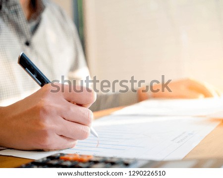 Business women writing on chart at home,selective focus hand holding pen.