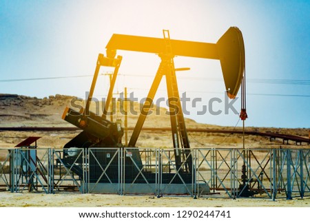 Typical crude oil pump jack from an oil field in the desert of Bahrain with sun, Middle East.vintage color