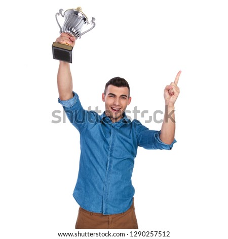 casual man holding cup in the air celebrates and points finger while standing on white background, portrait picture