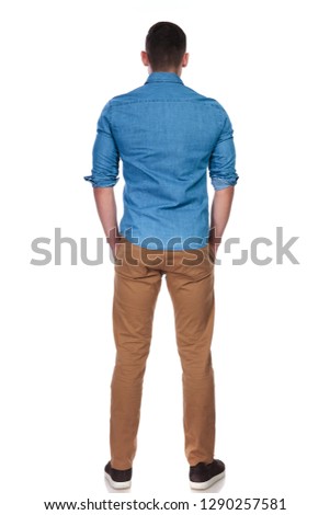 back view of young and relaxed casual man standing on white background with hands in pockets, full length picture