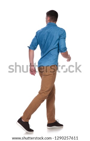 handsome casual man steps to side on white background and looks behind, full length picture